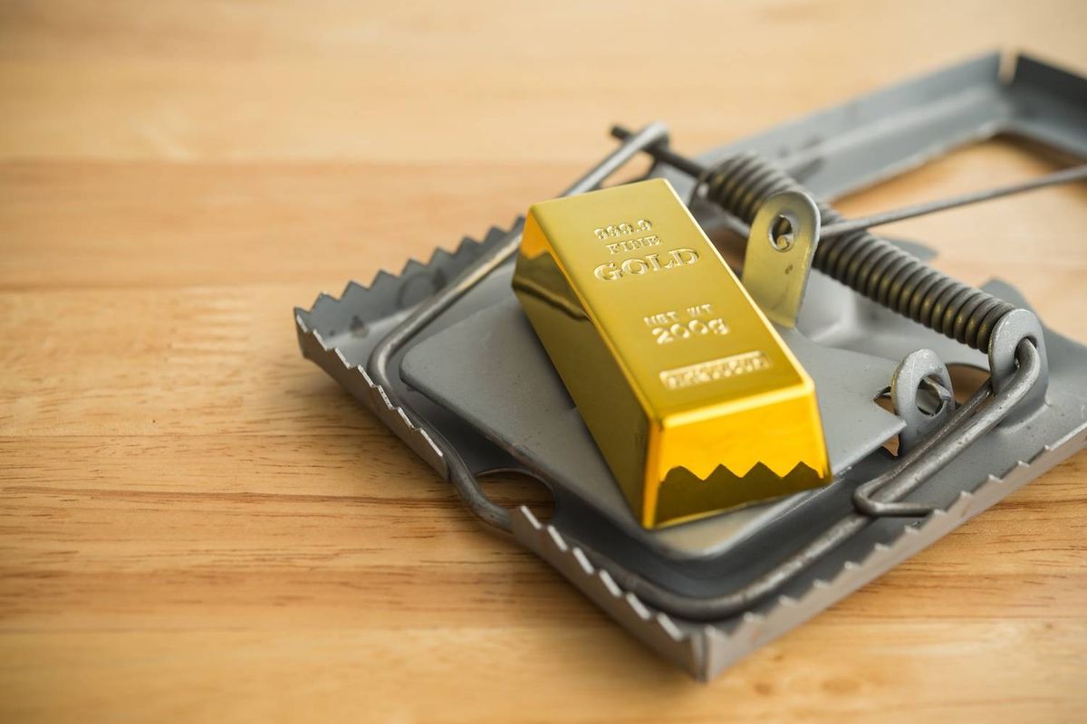 Gold bar placed on a large metal trap on a wooden surface.