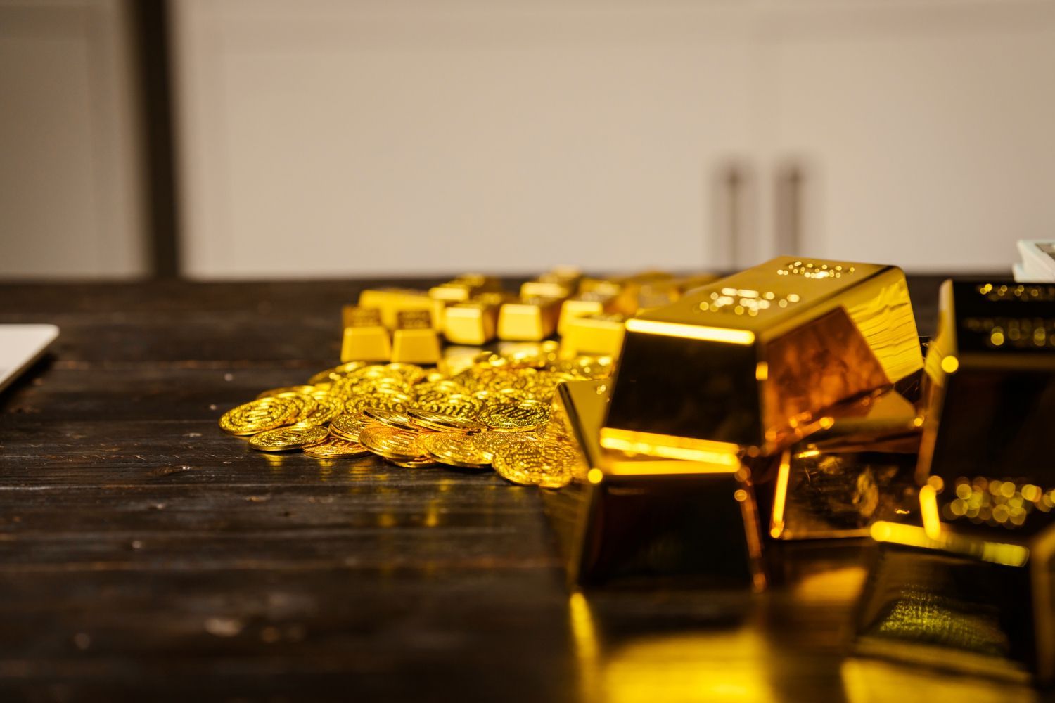 Gold bars and coins on a dark wooden table.