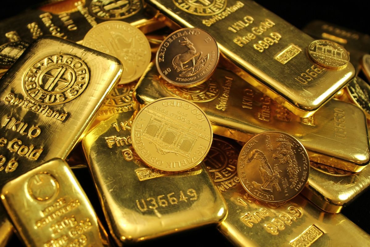 Gold bars and coins stacked on each other, reflecting light.