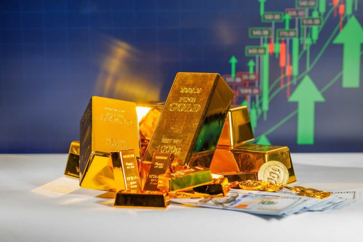 Gold bars, coins, and cash with financial chart and green arrows in the background.