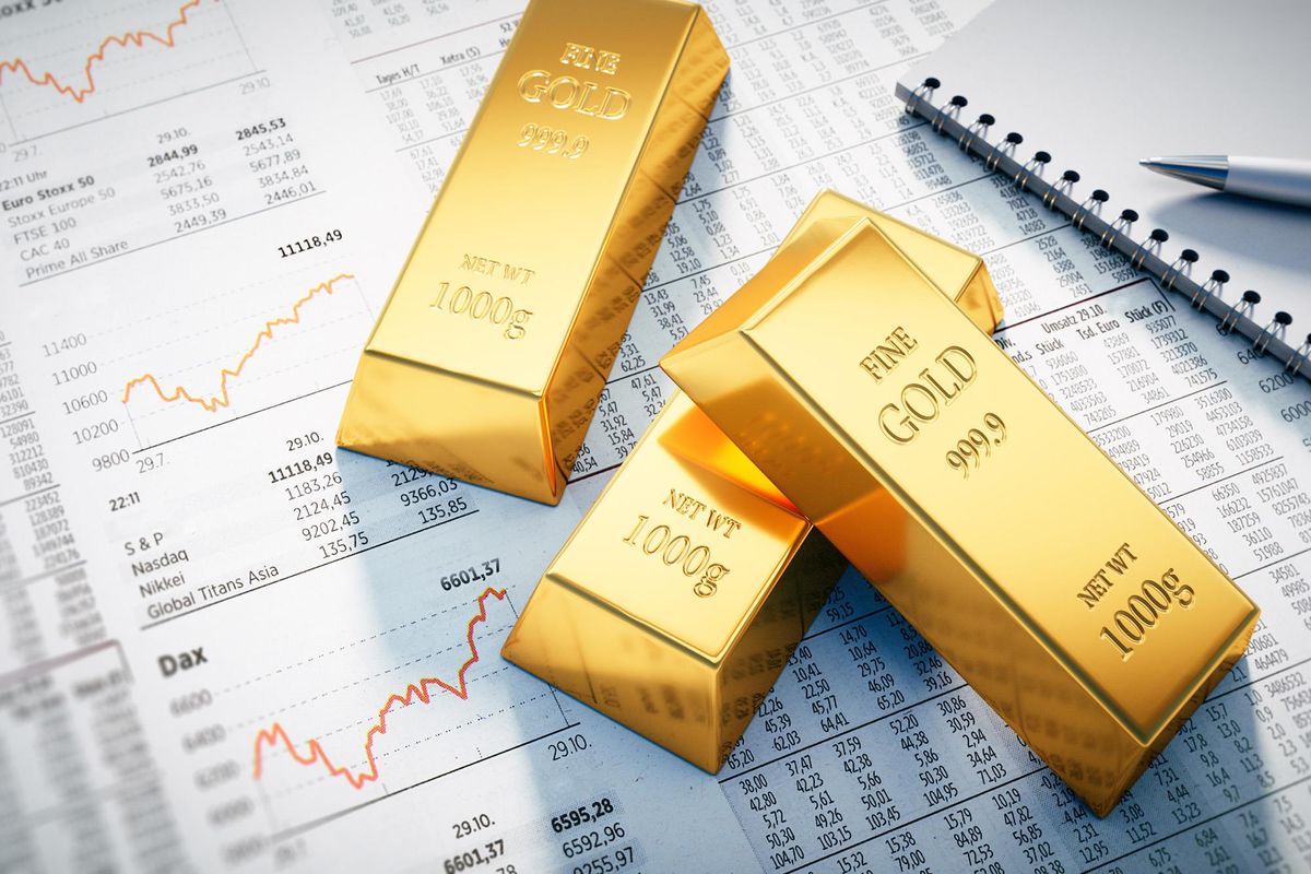 Gold bars on top of papers showing stock exchange numbers.