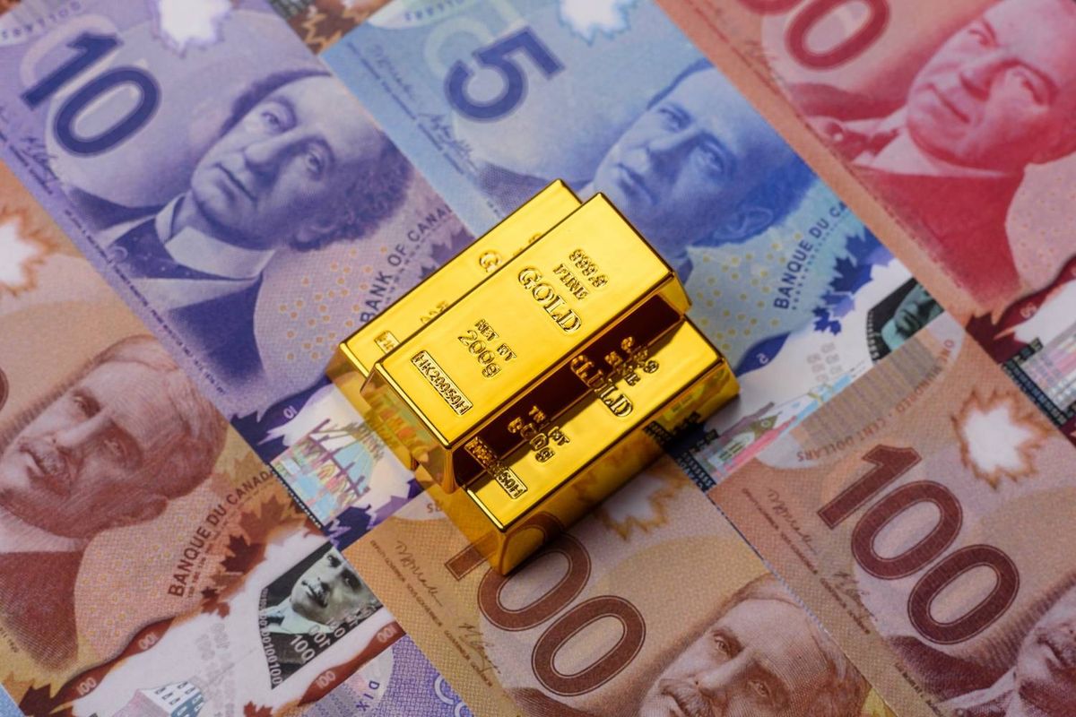 Gold bars rest on overlapping Canadian banknotes, including denominations of 5, 10, 50, and 100 dollars.