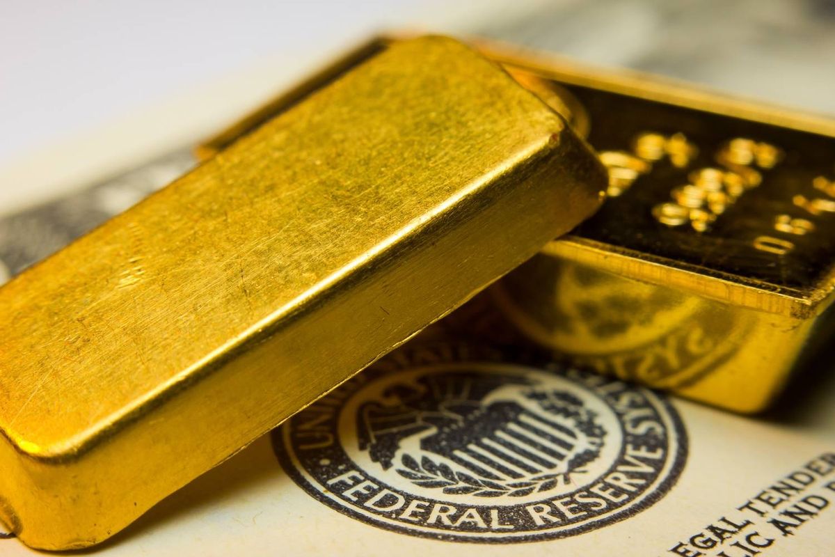 Gold bars resting on a Federal Reserve document with emblem and partial visible text.
