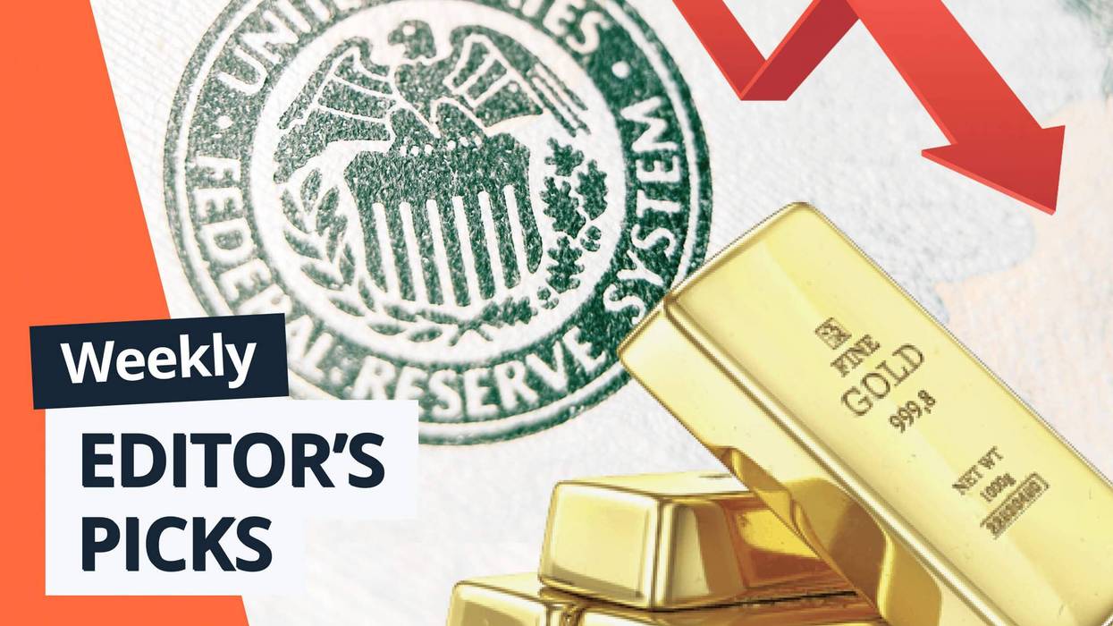 Gold bars stacked in front of US Federal Reserve seal, with red downward arrow.