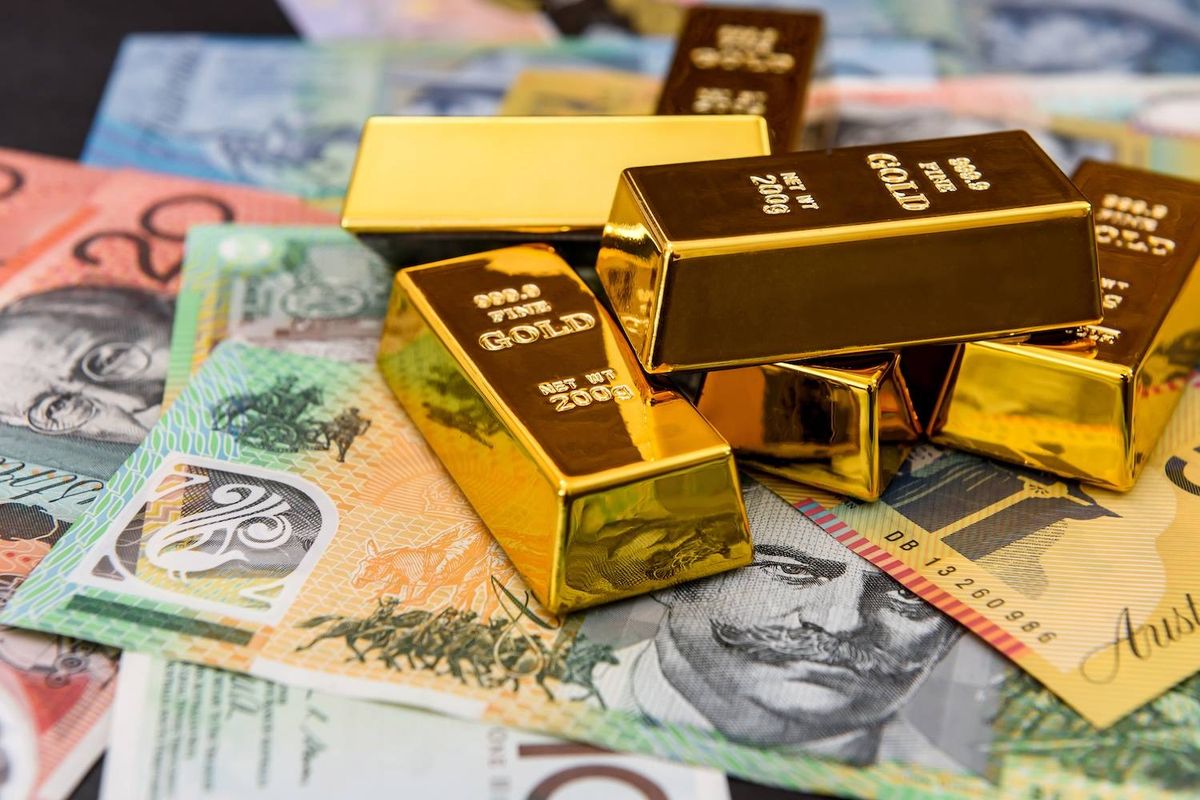 Gold bars stacked on colorful Australian banknotes.