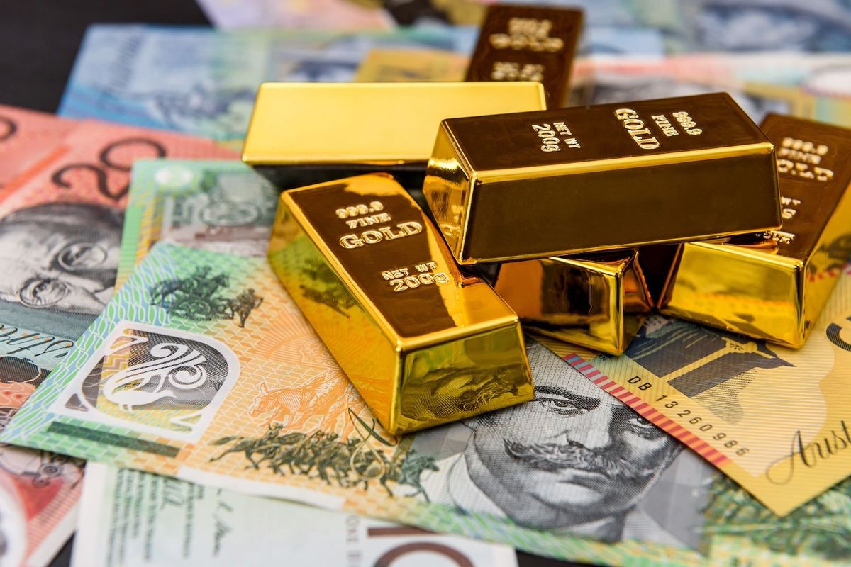 Gold bars stacked on colorful currency notes.