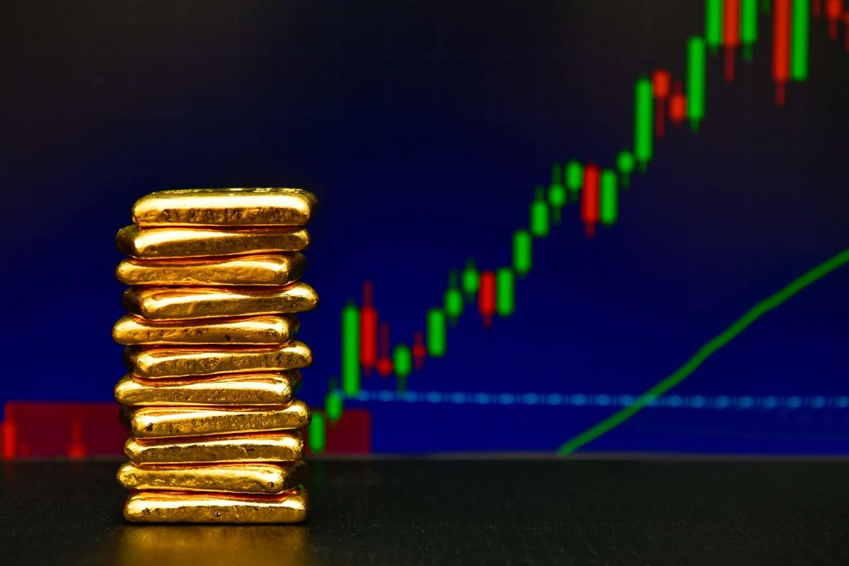 Gold bars stacked, with a rising financial chart in the background.