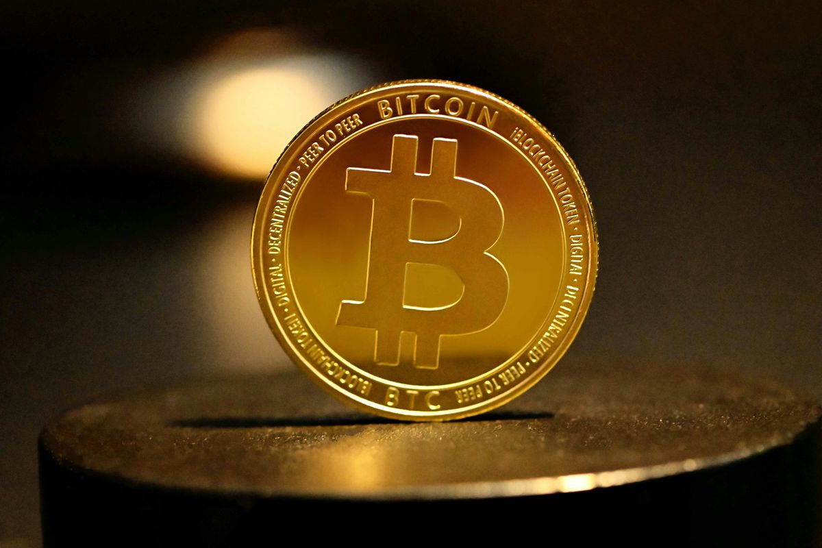 Gold Bitcoin coin on a black surface with a dark background.