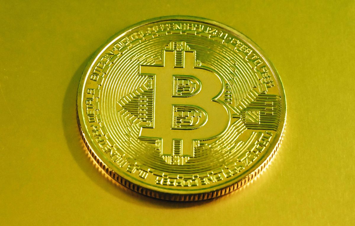 Gold Bitcoin coin with a digital circuit pattern on a yellow background.
