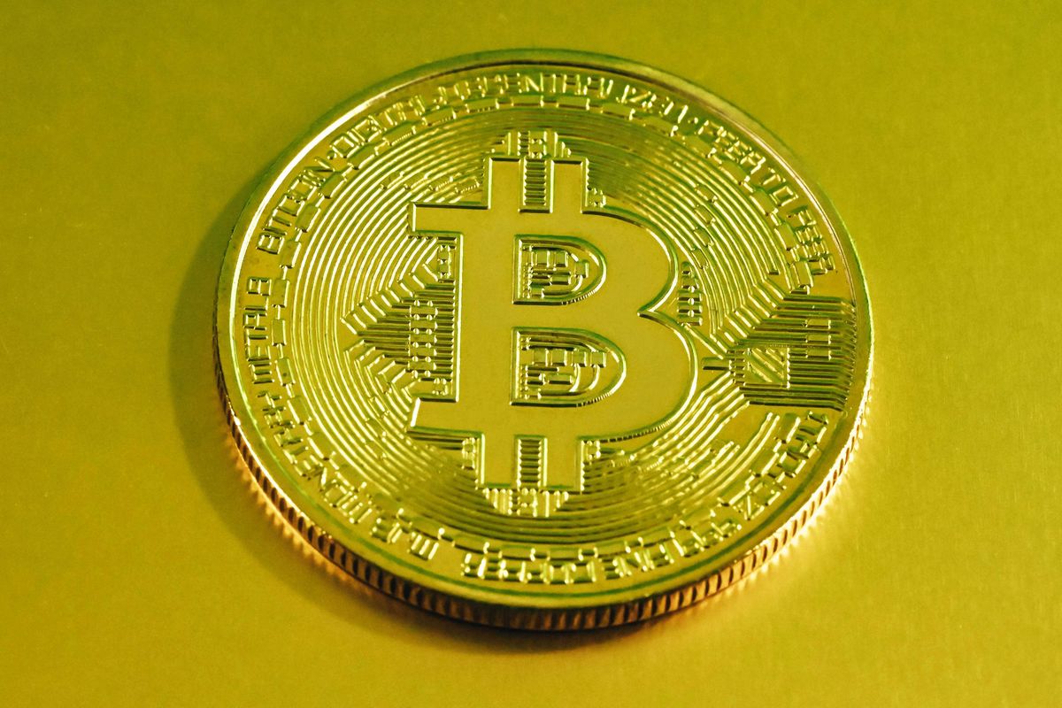 Gold Bitcoin coin with a digital circuit pattern on a yellow background.