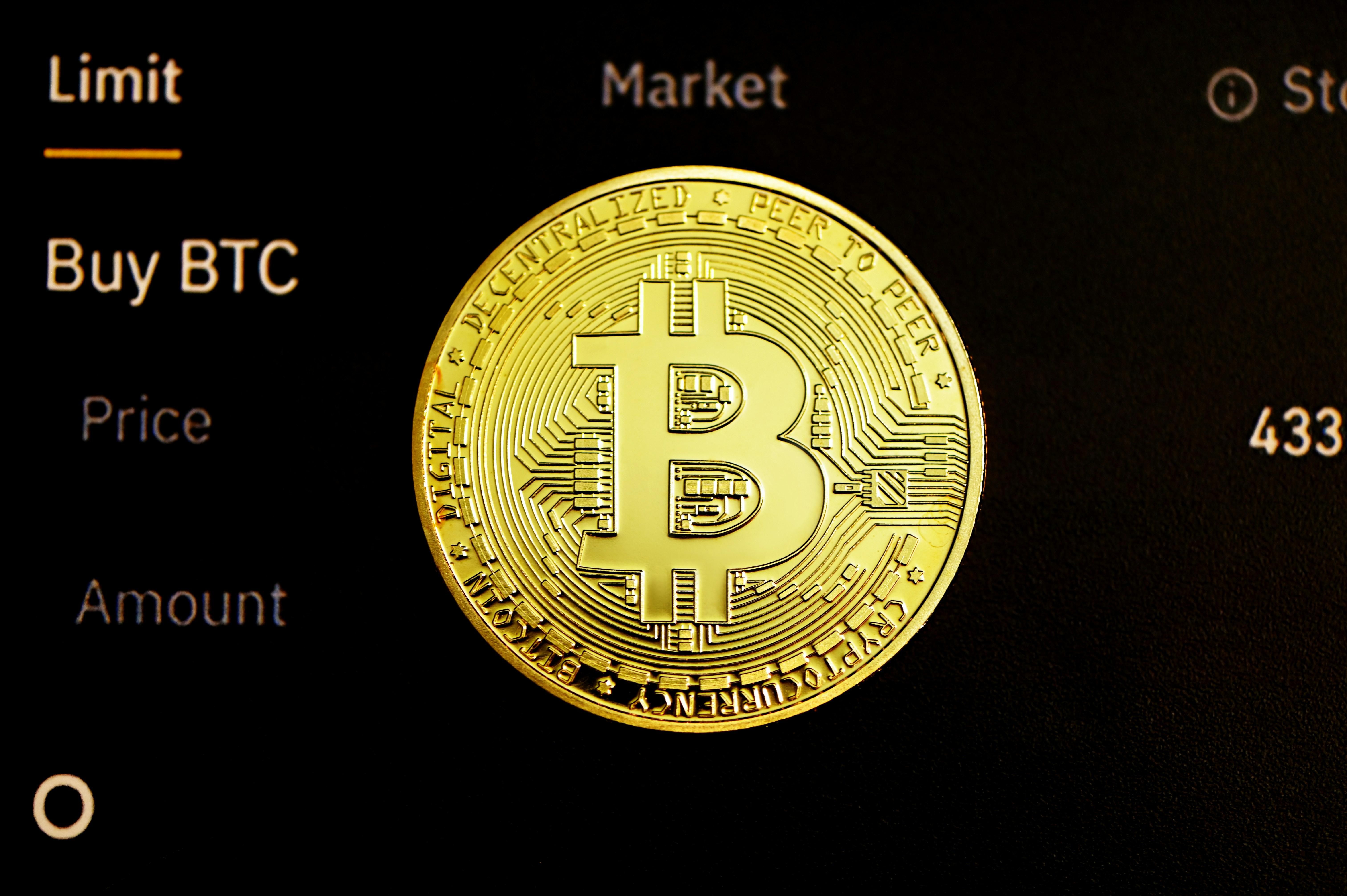 Gold Bitcoin over a digital market dashboard displaying "buy BTC" option.