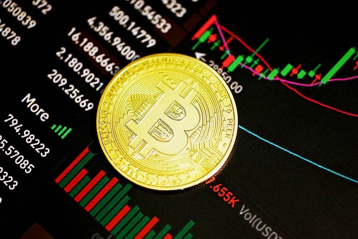 Gold Bitcoin rests on digital chart with red and green bars.