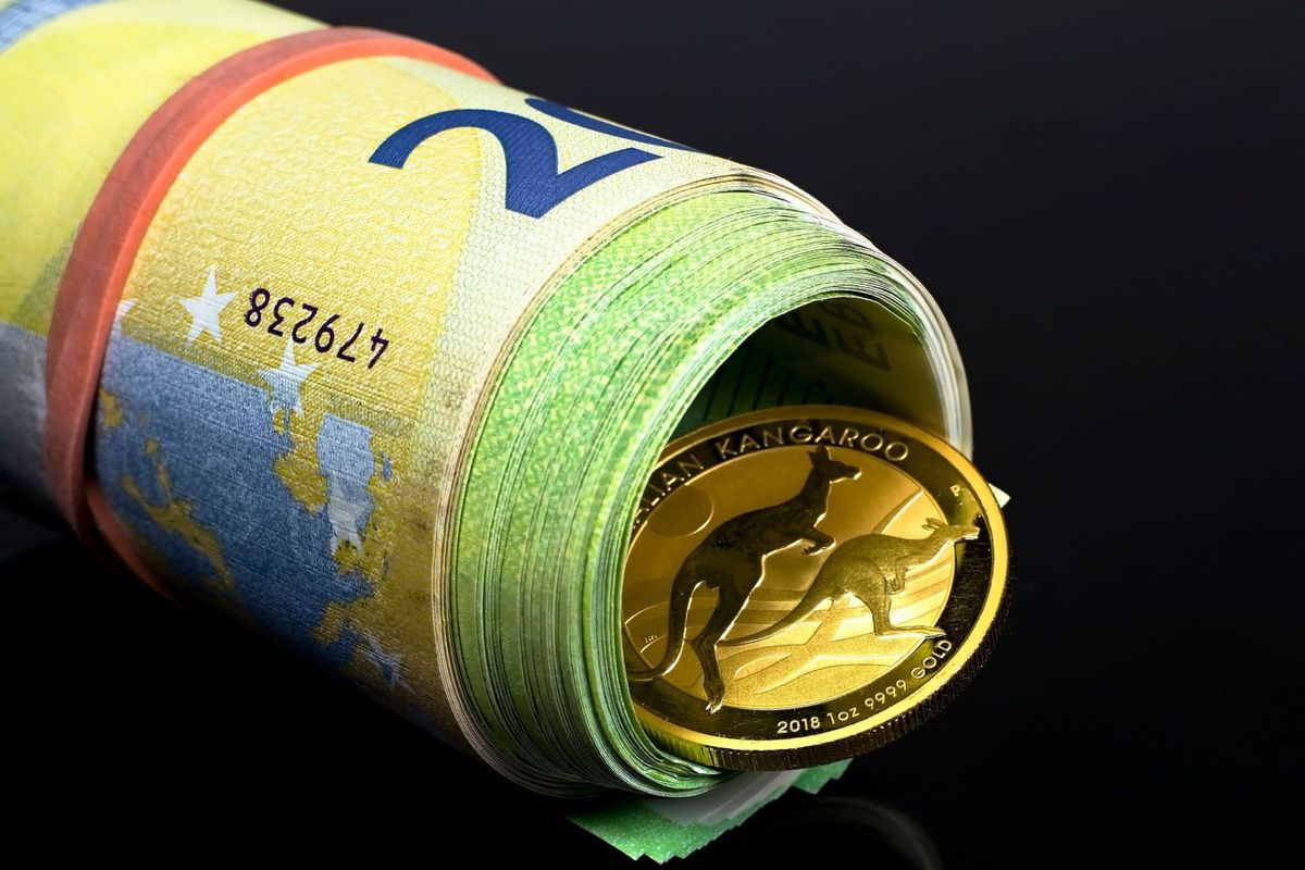 Gold coin in rolled up Australian bills.