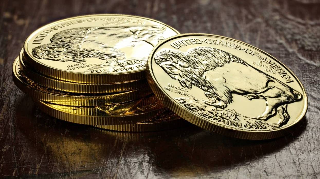 Gold coins featuring a buffalo design stacked on a dark wooden surface.