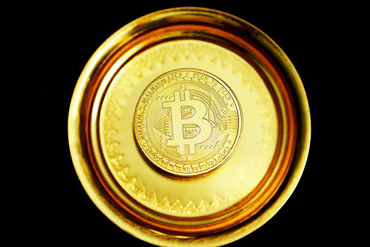 Golden Bitcoin coin on black background, viewed from above.