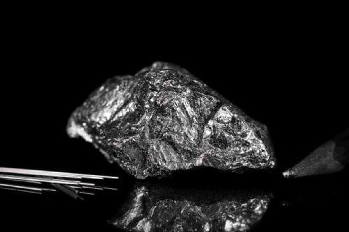 Graphite ore on a black mirror surface.