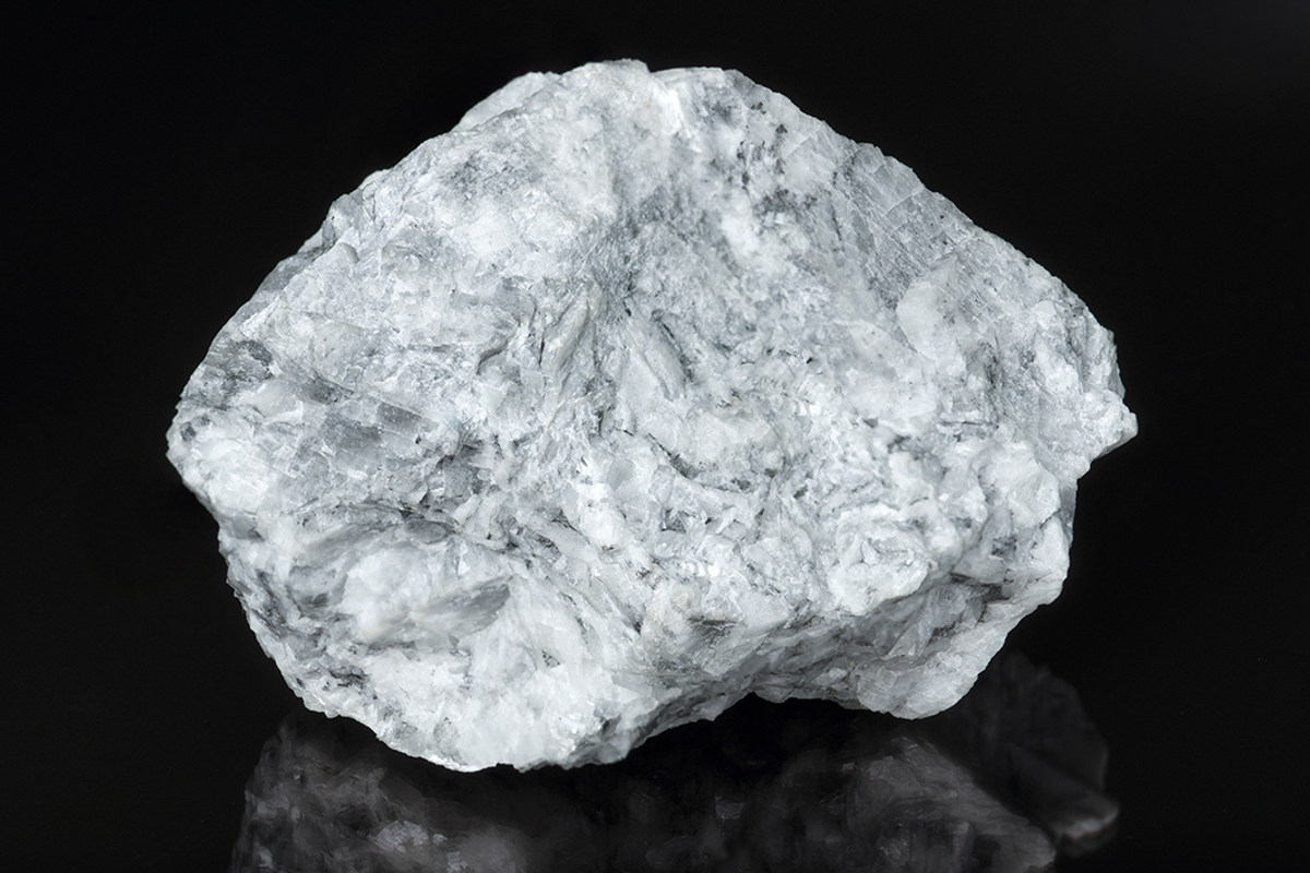Gray-blue sodalite rock with white veins on a black background.