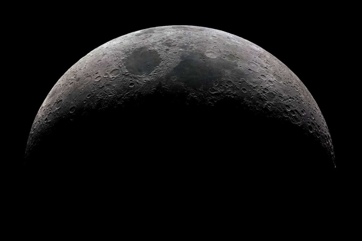Half-lit crescent moon with visible craters against a black sky.