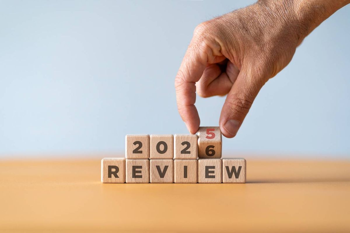 Hand changing blocks from 2025 to 2026 above the word "REVIEW".
