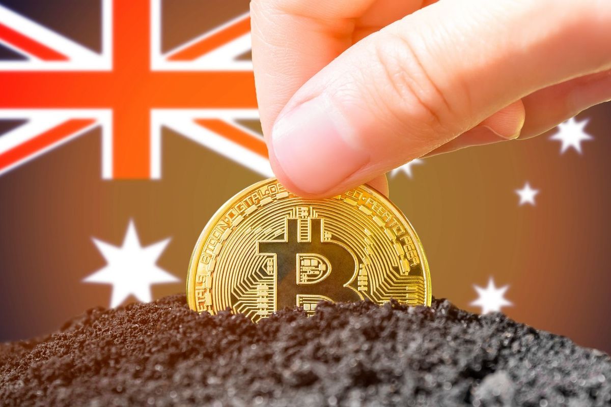 Hand holding a Bitcoin above soil, with an Australian flag background.