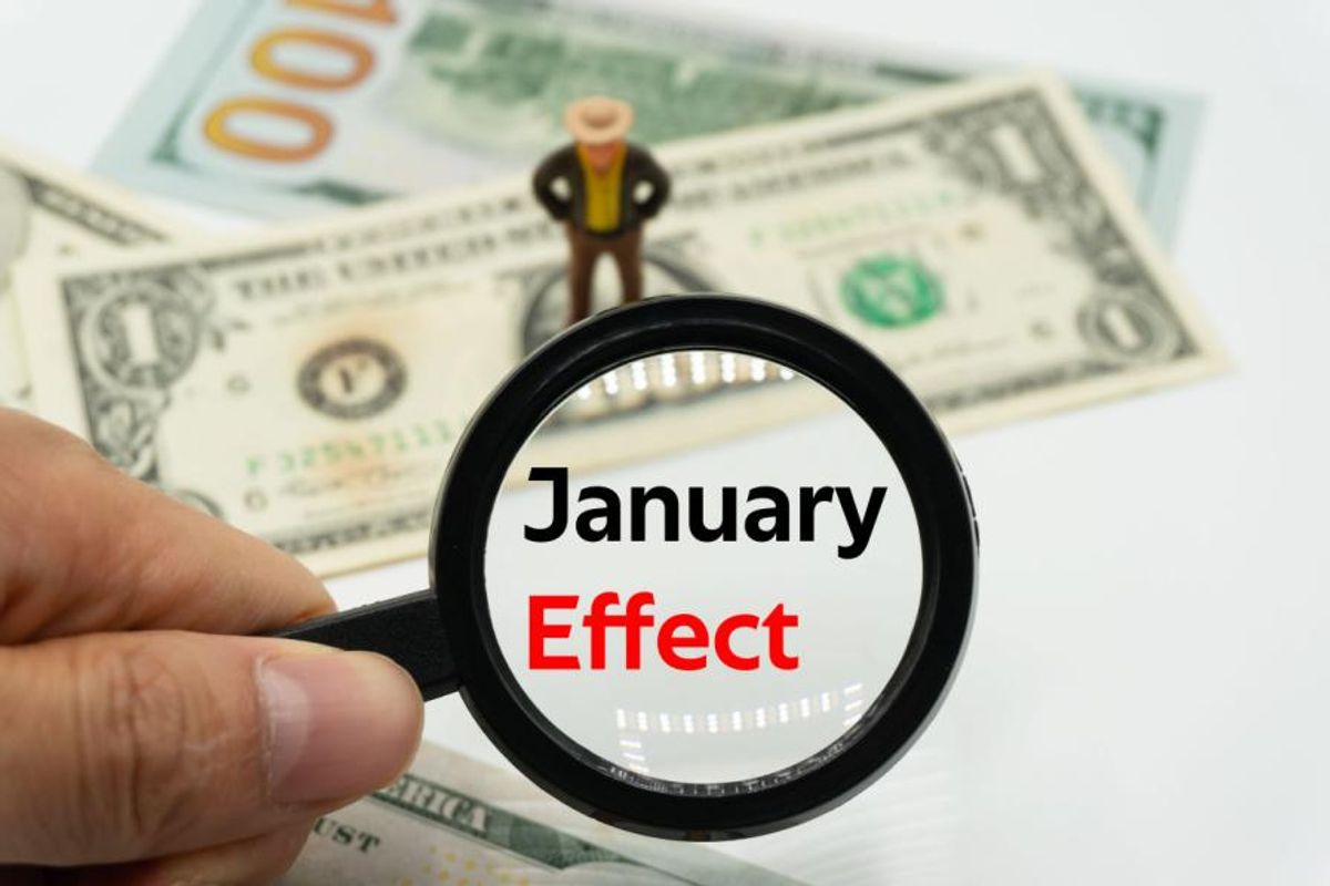 Hand holding magnifying glass with words "january effect" inside.