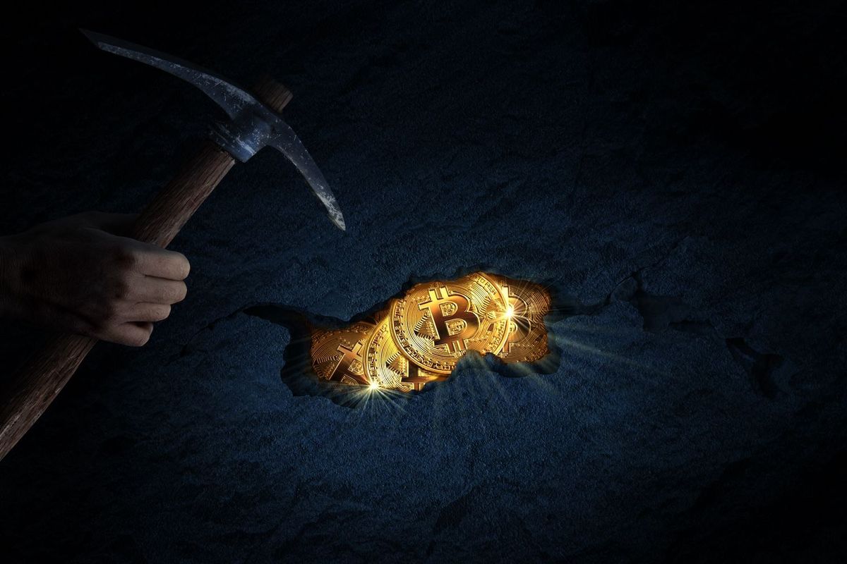 Hand holding pickaxe, mining for Bitcoin on a dark rock surface.