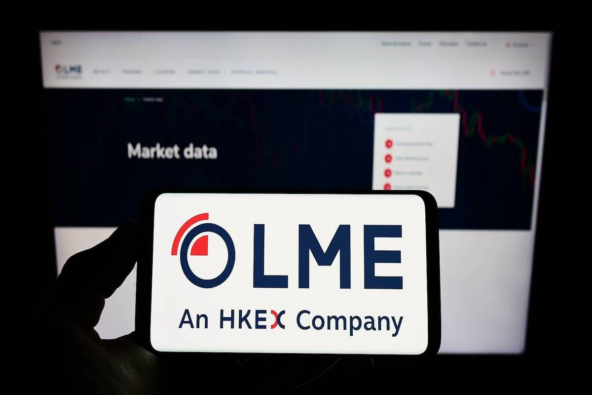 Hand holding smartphone displaying LME logo, website background reads "Market data".