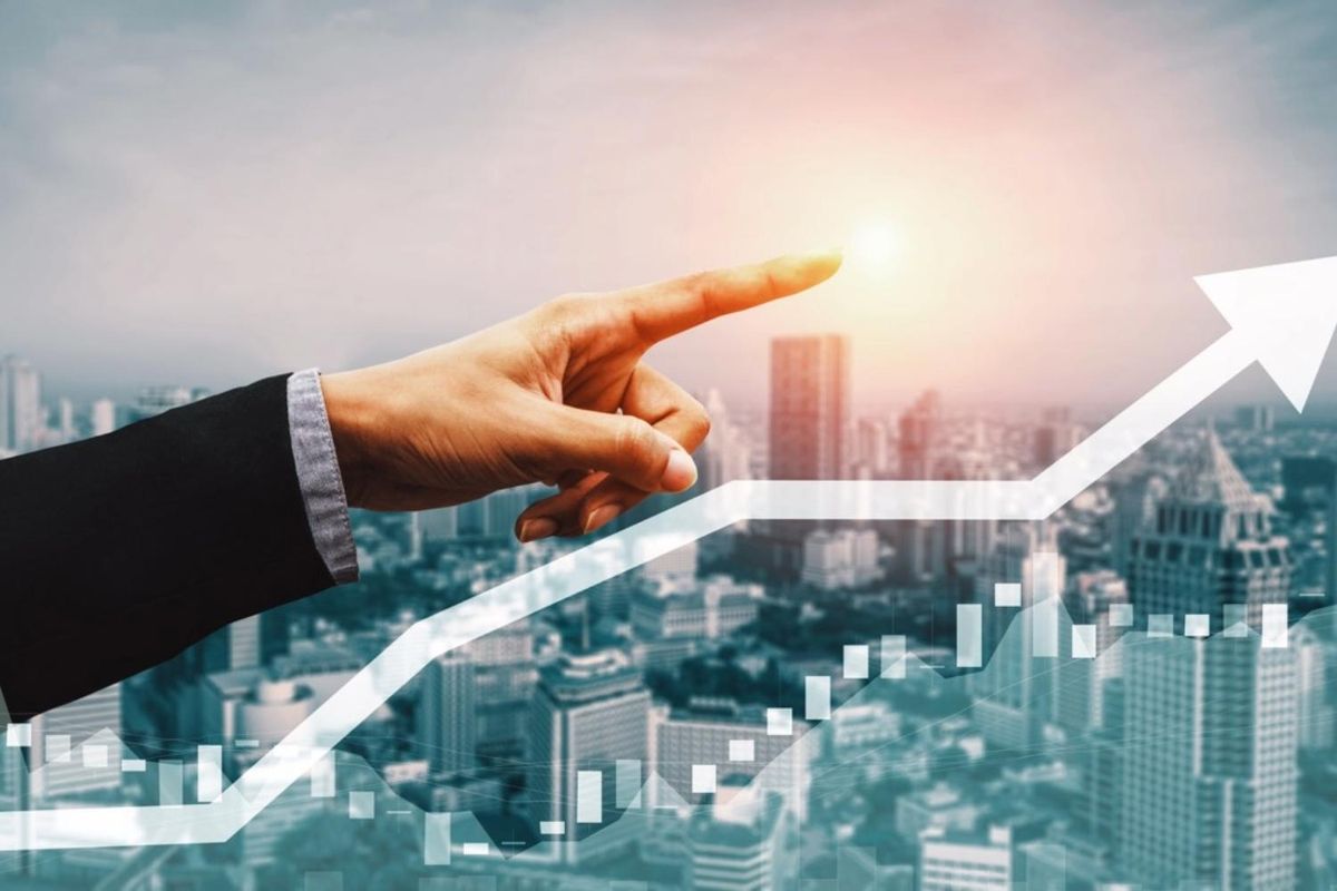 Hand pointing at glowing sun over rising stock chart, cityscape background.