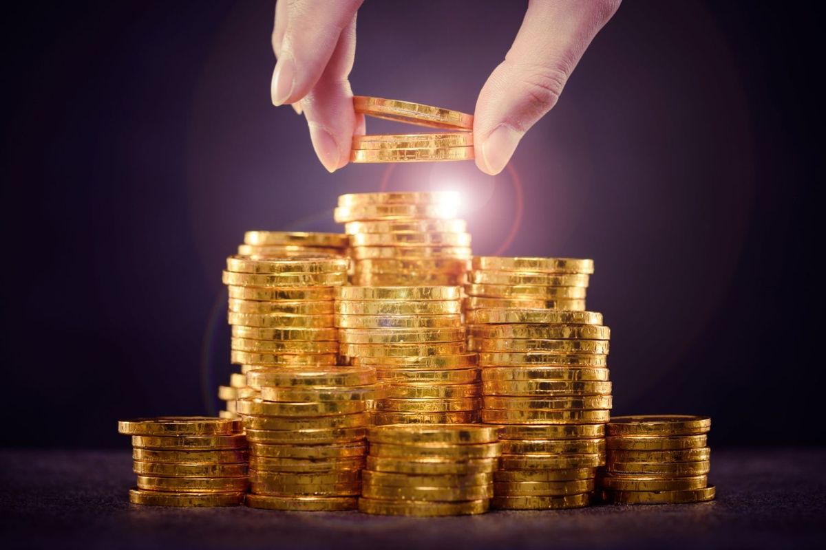 Hand stacking gold coins.