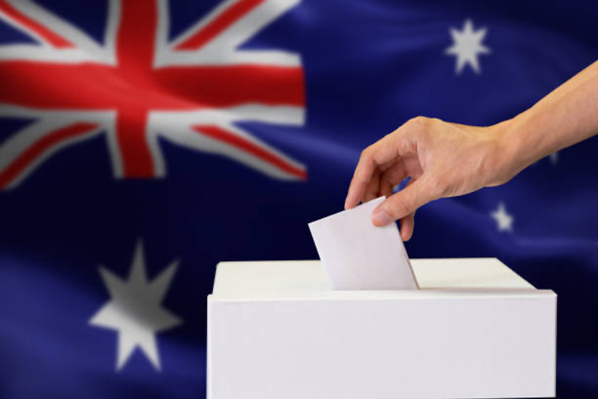 Hand voting with Australian flag in background.