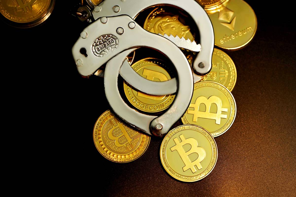 Handcuffs on cryptocurrency coins: Bitcoin, Ethereum, Dogecoin.