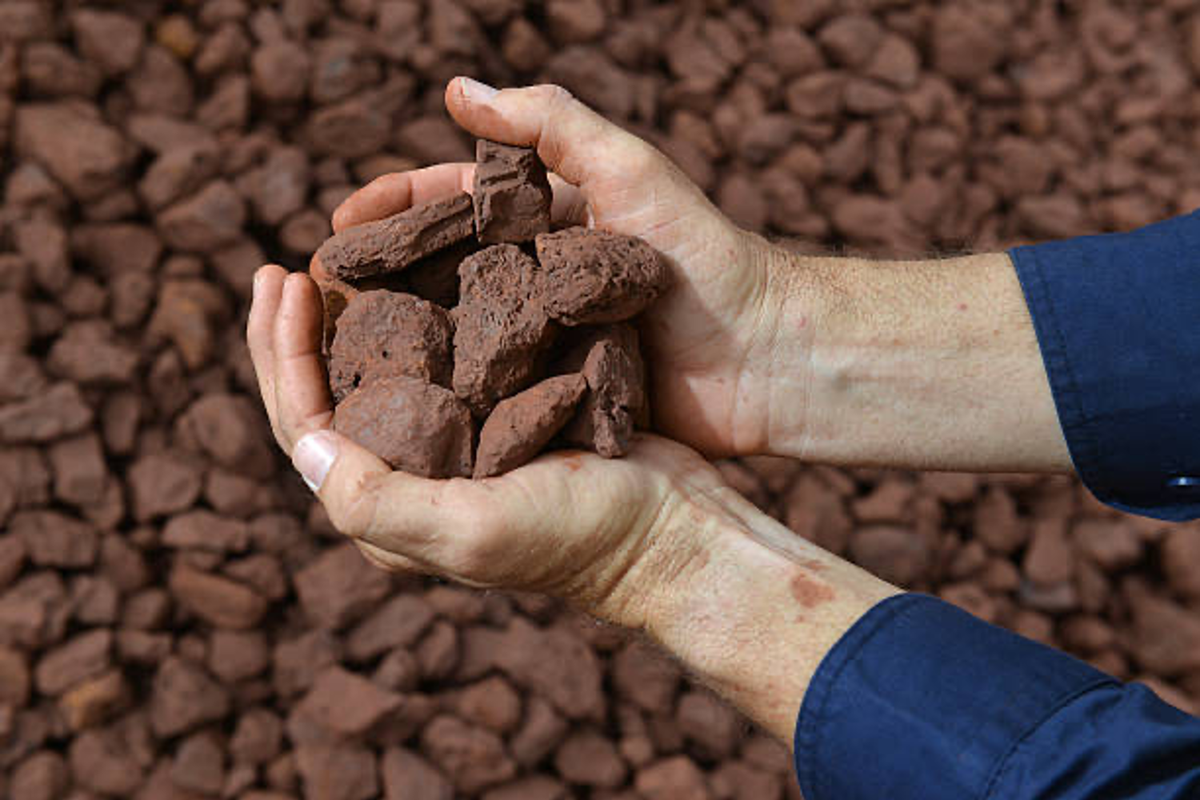 Hands holding crushed iron ore.