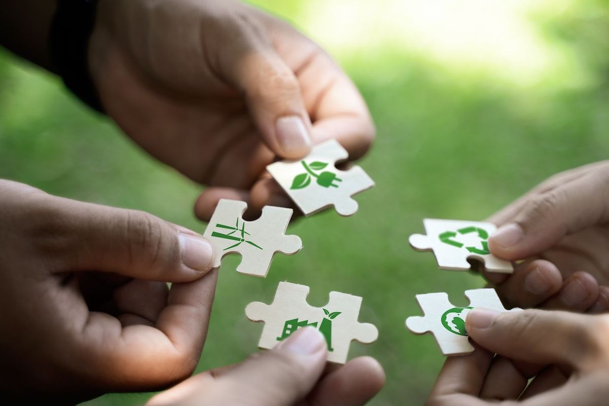 Hands holding eco-themed puzzle pieces with green symbols.