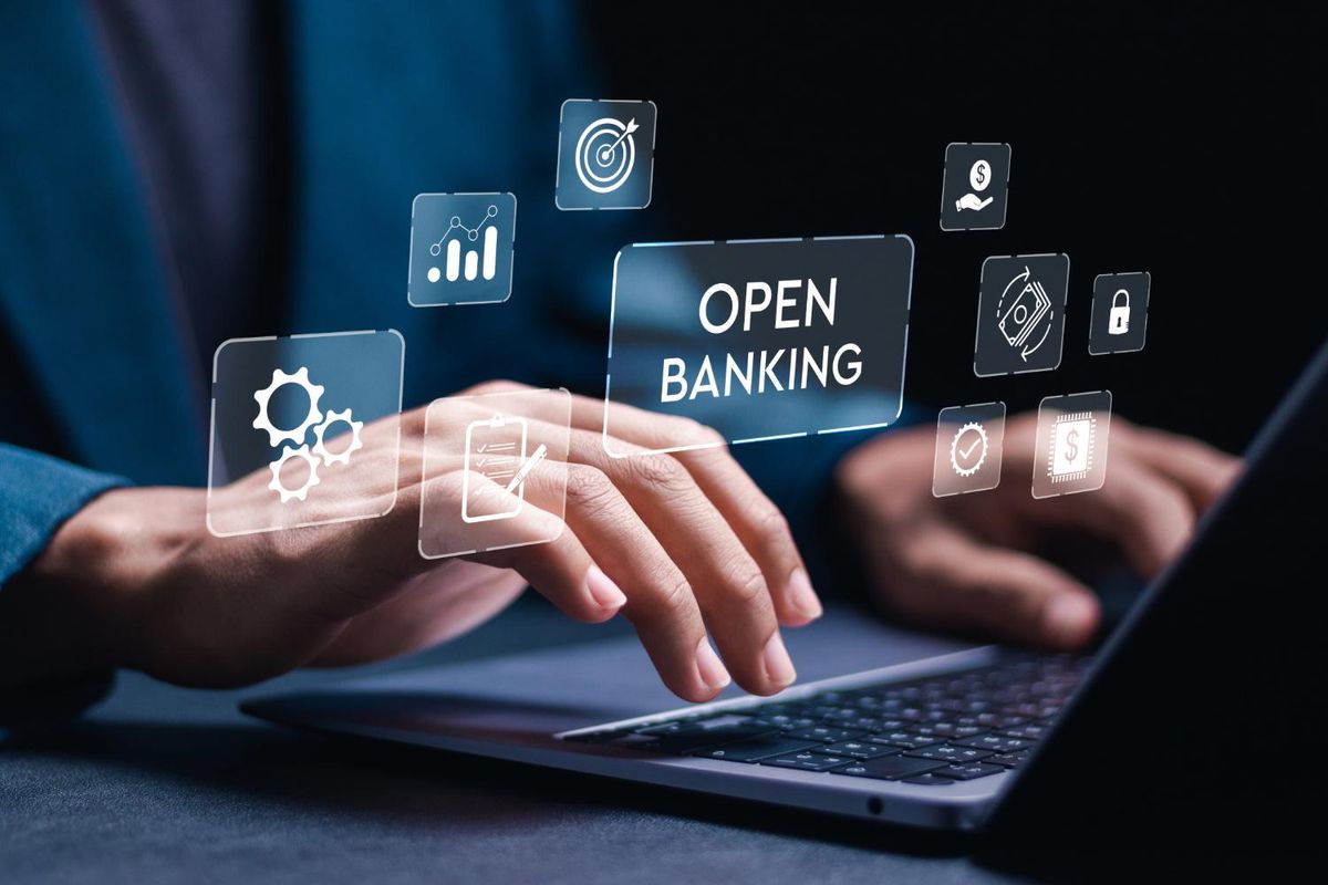 Hands typing on a laptop with "open banking" text and related icons hovering above.