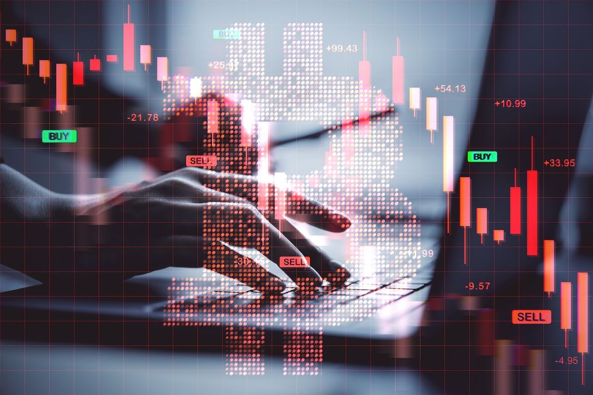 Hands typing with overlay of financial charts and a digital Bitcoin symbol.