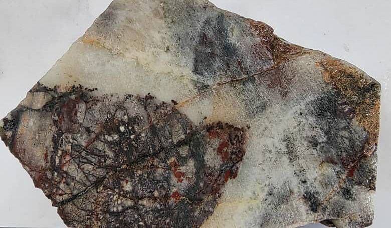 Pervasively silicified and fractures fragments of tuffaceous wallrock, with hematite and goethite fracture fill, forming part of a saccharoidal quartz vein which is partly dark grey and sulphidic.