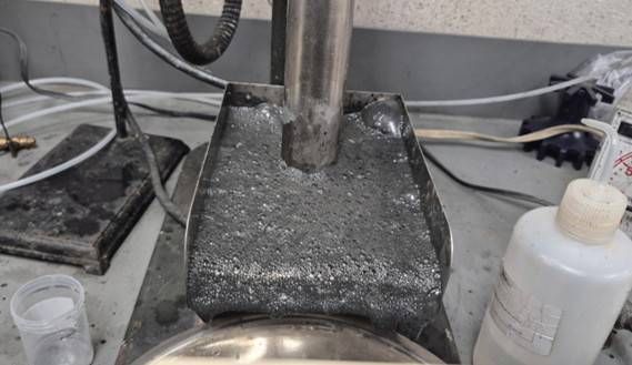 Preliminary metallurgical test of composite material from RPM zone at Pipestone XL project, picture showing the rougher flotation stage. The metallic surface visible on-top of liquid within a bench scale flotation cell is awaruite particles attaching to the surface of bubbles and floating to the top to be collected and cleaned in a multi-stage process isolating and concentrating the awaruite nickel–iron-cobalt alloy metal.
