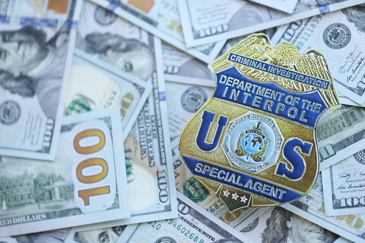 Interpol badge and U.S. currency spread out on a surface.