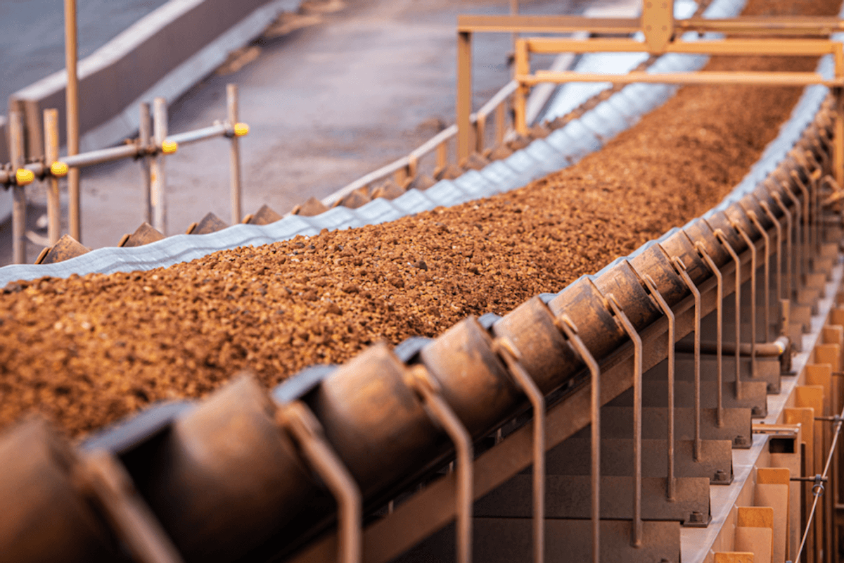 Iron ore on conveyor belt in mining process.
