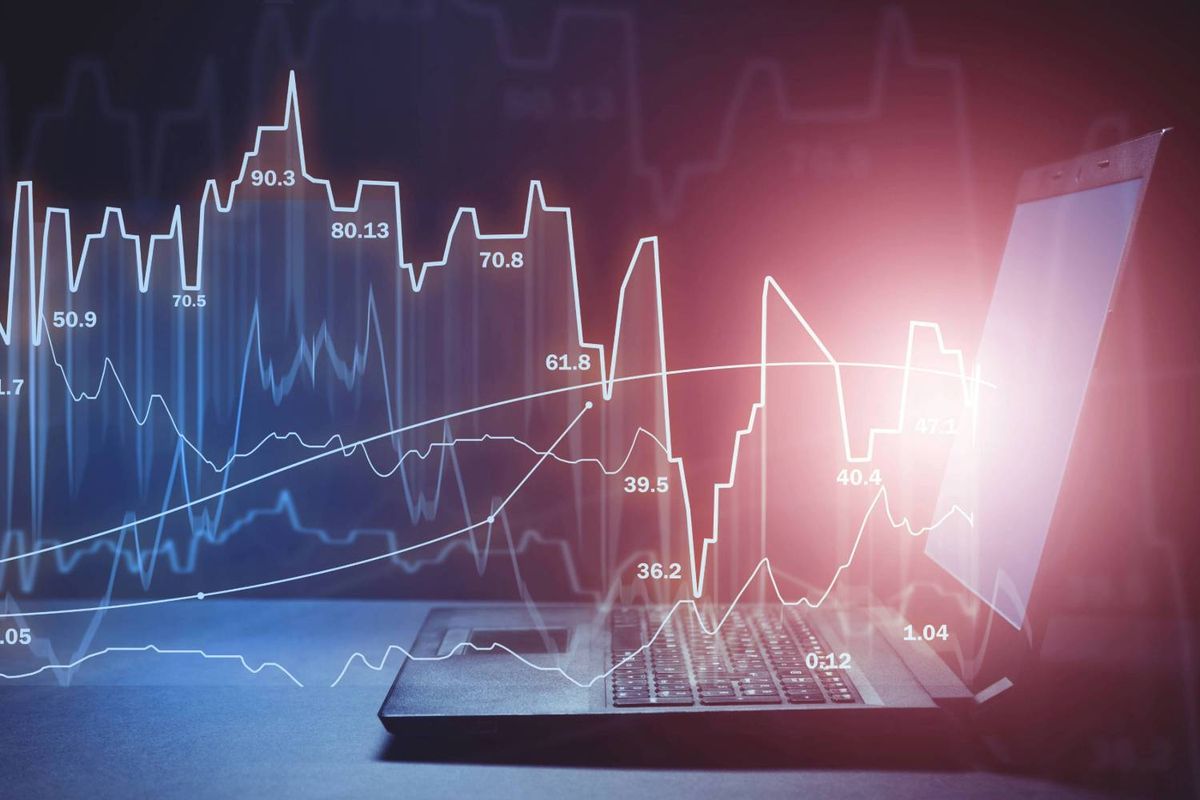 Laptop with overlay of fluctuating financial graphs and data points.