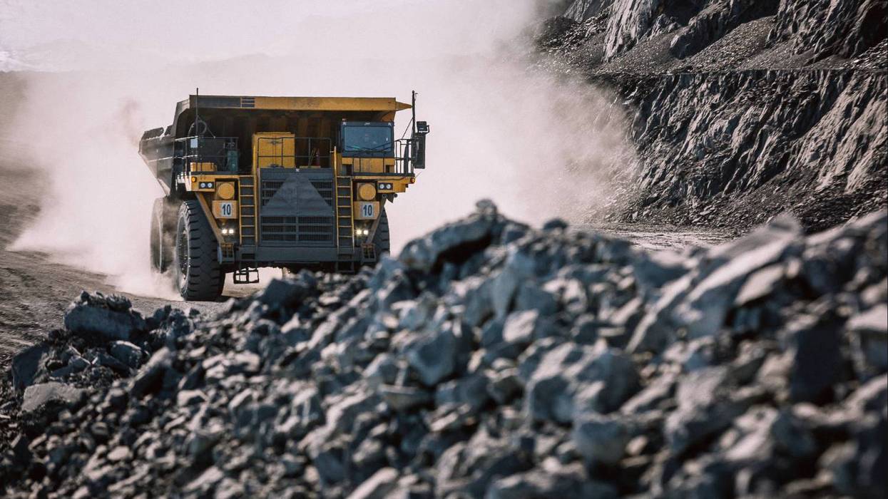 Large dump truck on dusty road in rocky quarry.