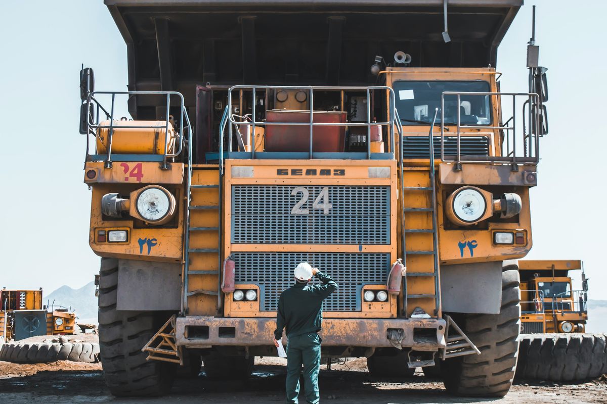 Large truck at mine site with worker looking up at it.