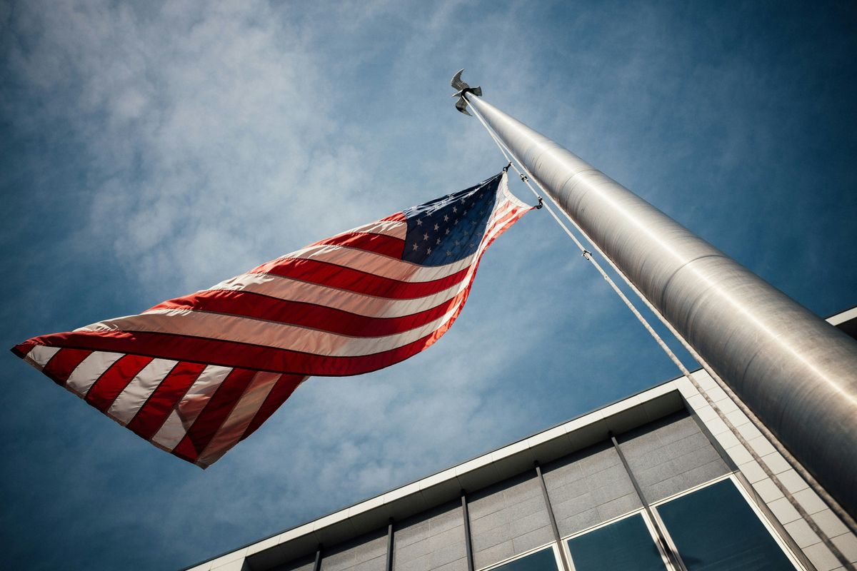 Low-angle photo of US flag placed on gray pole.