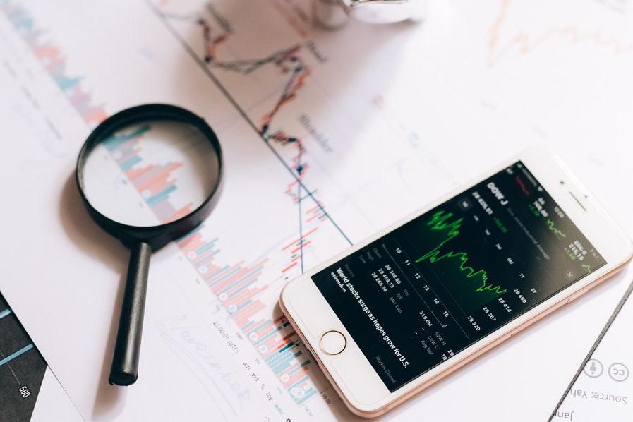 magnifying glass and phone with stock charts