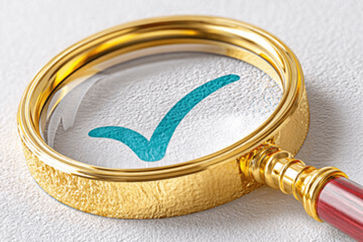 magnifying glass with gold detail above a check mark.