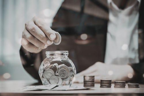man dropping coins into glass bowl
