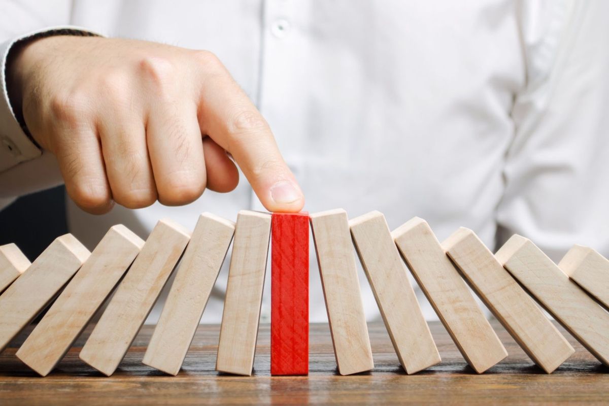 Man holds red domino upright.