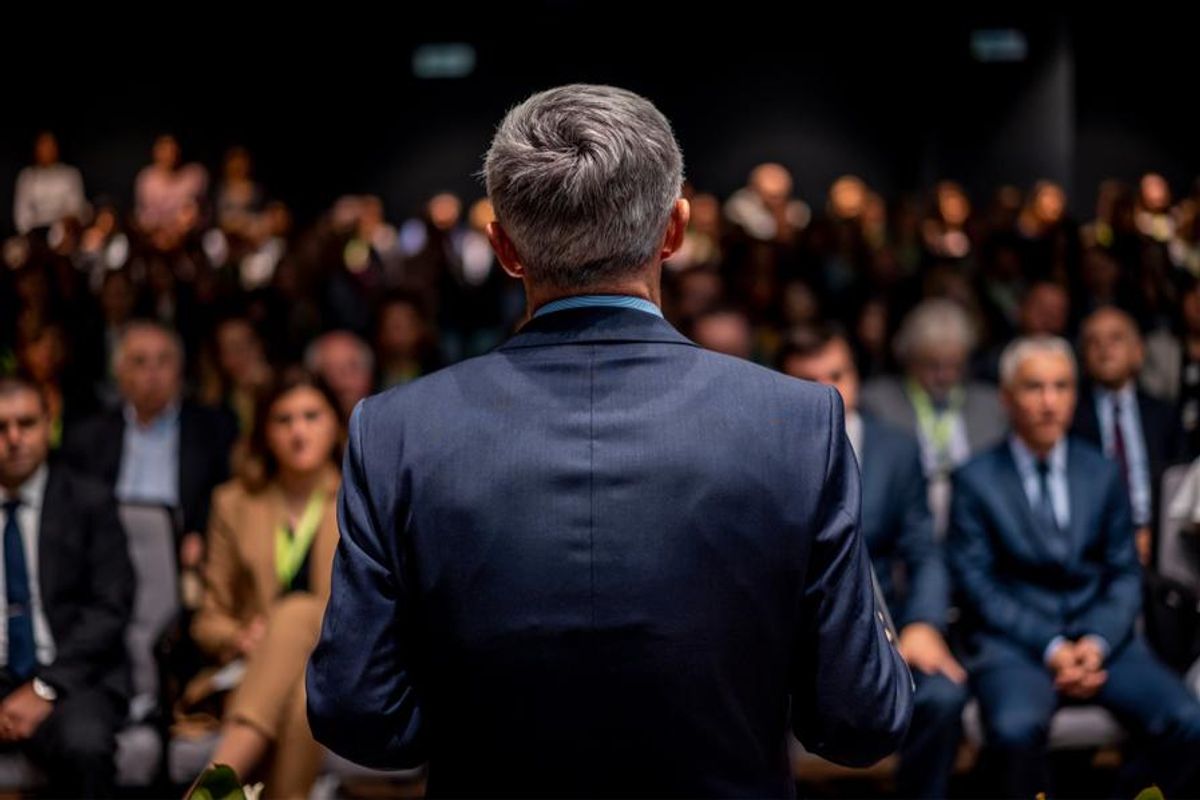 man in suit stands in front of an audience