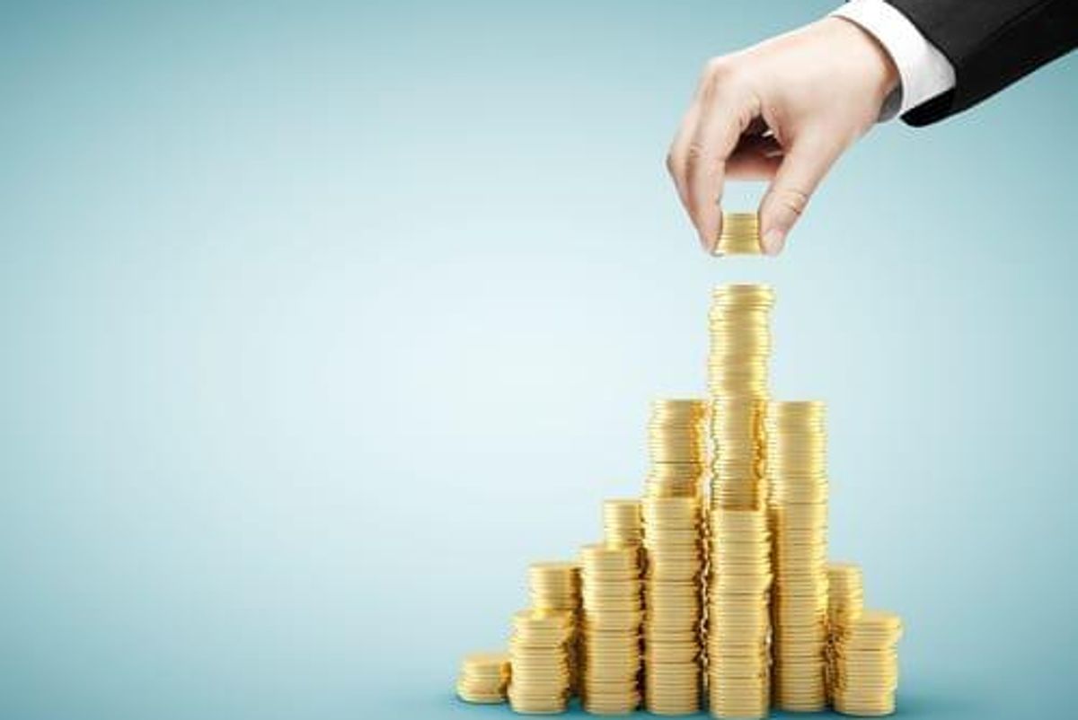 many piles of coins, with one taller than the rest. a hand is adding more coins to that pile.