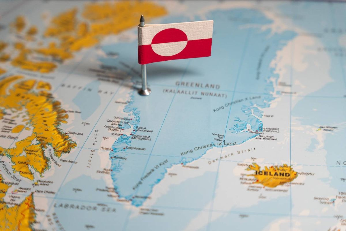 Map highlighting Greenland with a flag pin featuring its national design.